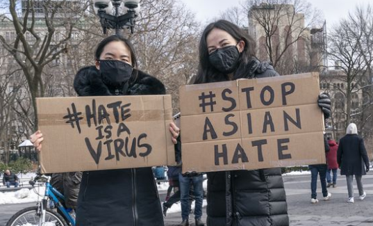 Protestors hold signs to show their support for the #stopasianhate movement