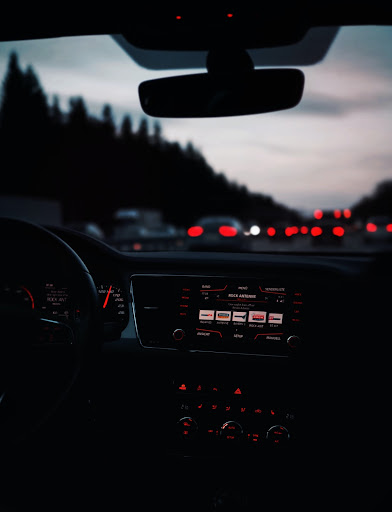  Cars drive on the slumbering highway, framed by forests in the background, as the night settles in.
