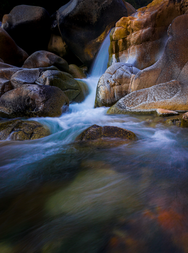 Mountain water slowly trickles down creating a beautiful mosaic of blue, brown, and green. 