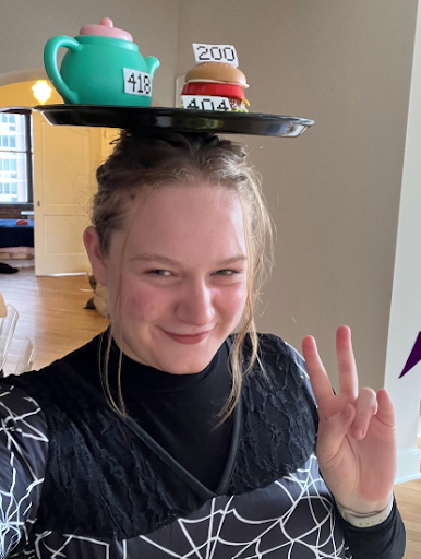 Adriana Davies (‘25) poses as a web server, complete with an apron, teapot, and hamburger. 